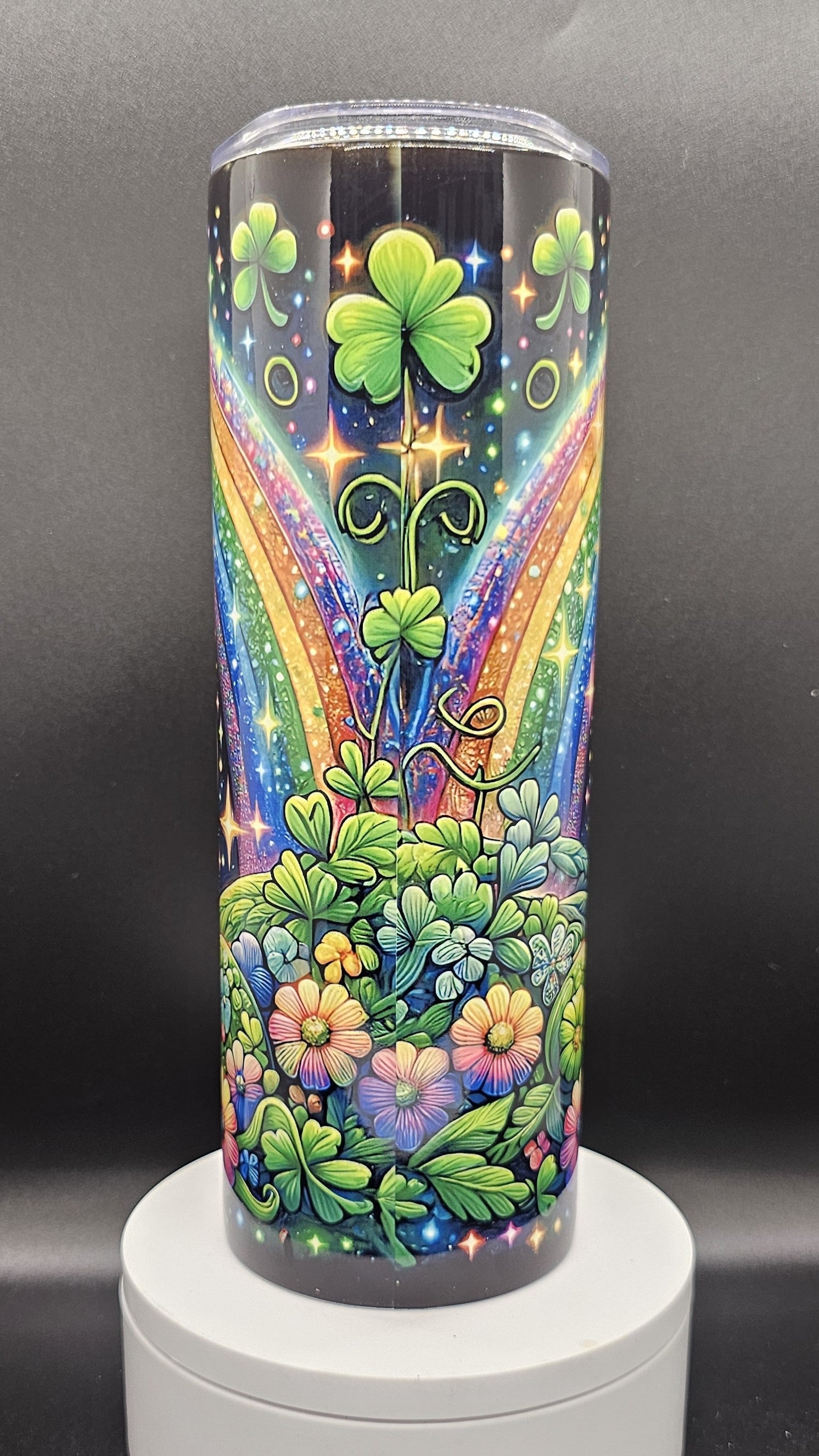 Colorful tumbler with shamrocks, flowers, and a rainbow on a dark background